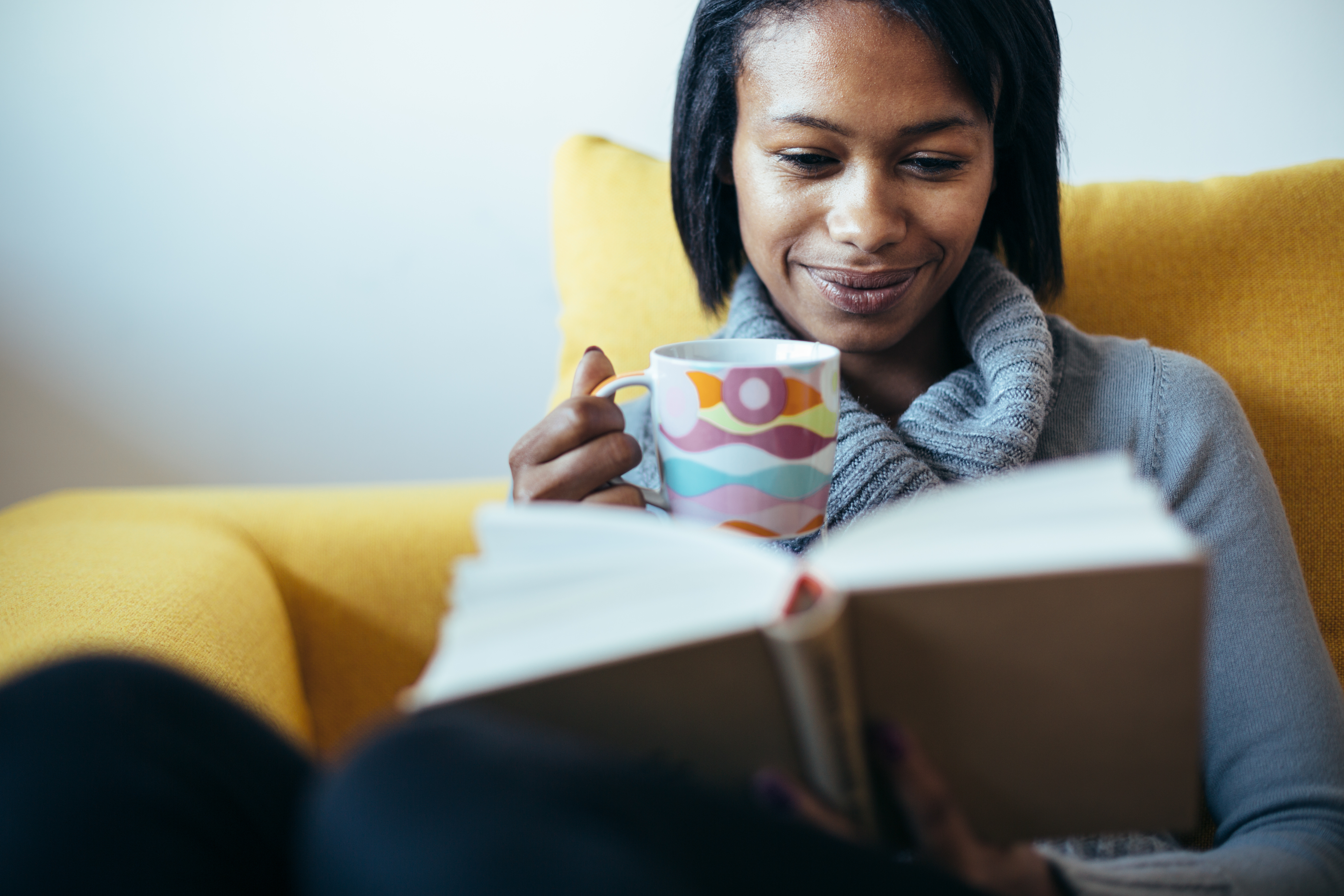 woman reading while holding a mug