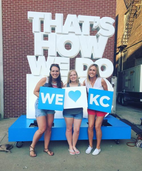 Taylor Russo and two friends in front of "That's how we do KC" sign