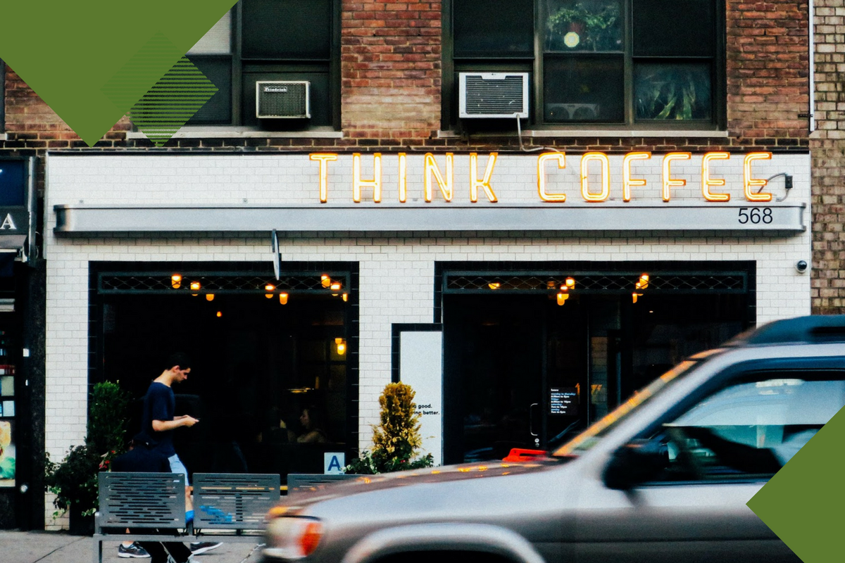 Man on phone walking past coffee shop called "think coffee" with dark green geometric shapes on top