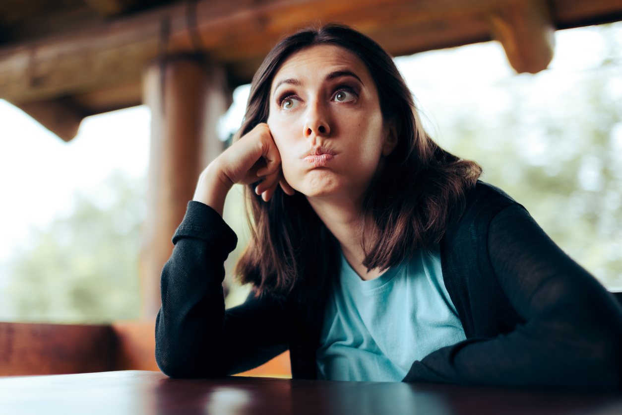 Impatient-looking woman sits with her head in her hand