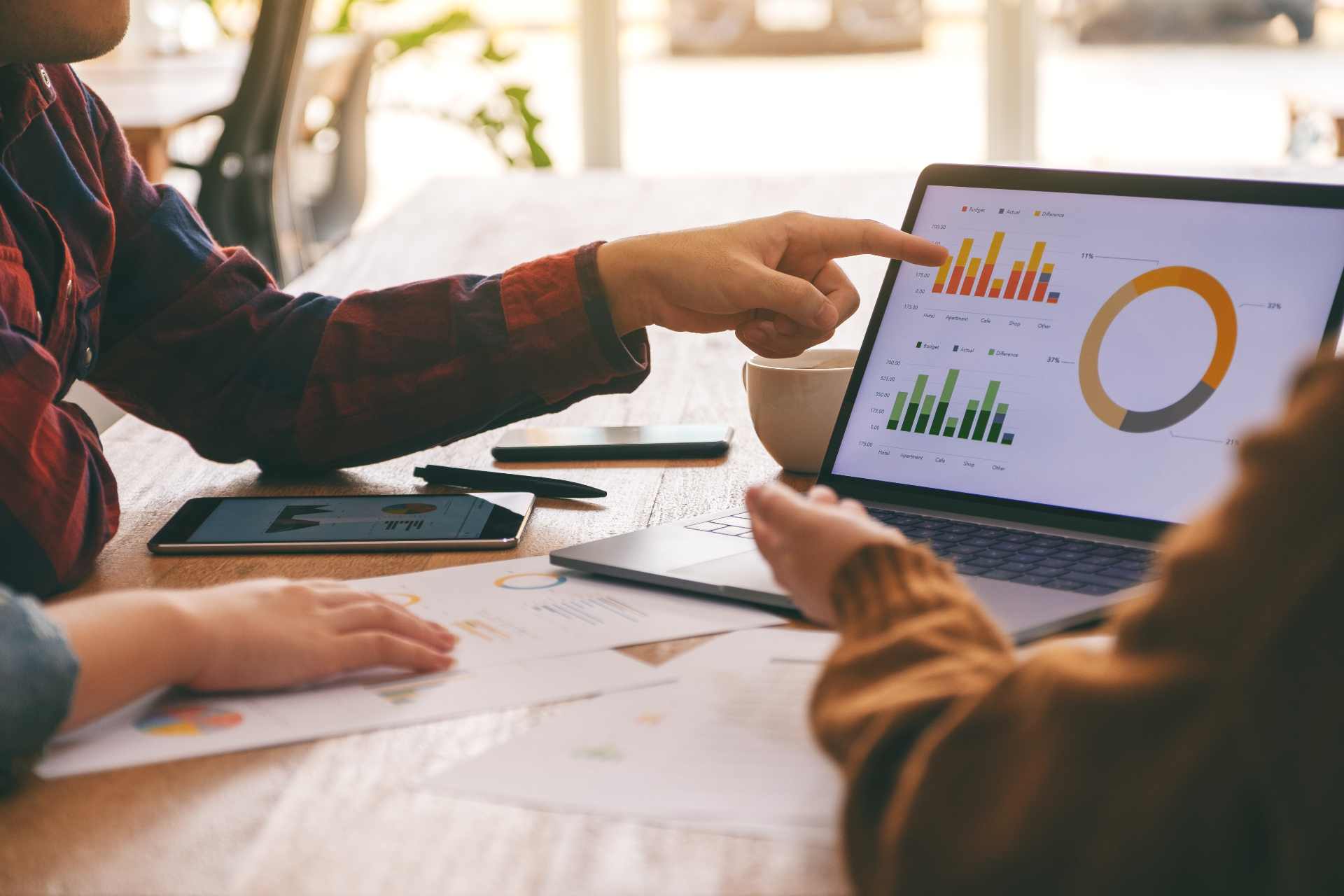 Two people viewing analytics and graphs on a tablet.