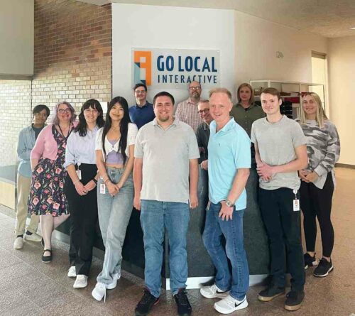 Our May hires standing together around the front desk at our Overland Park headquarters. 